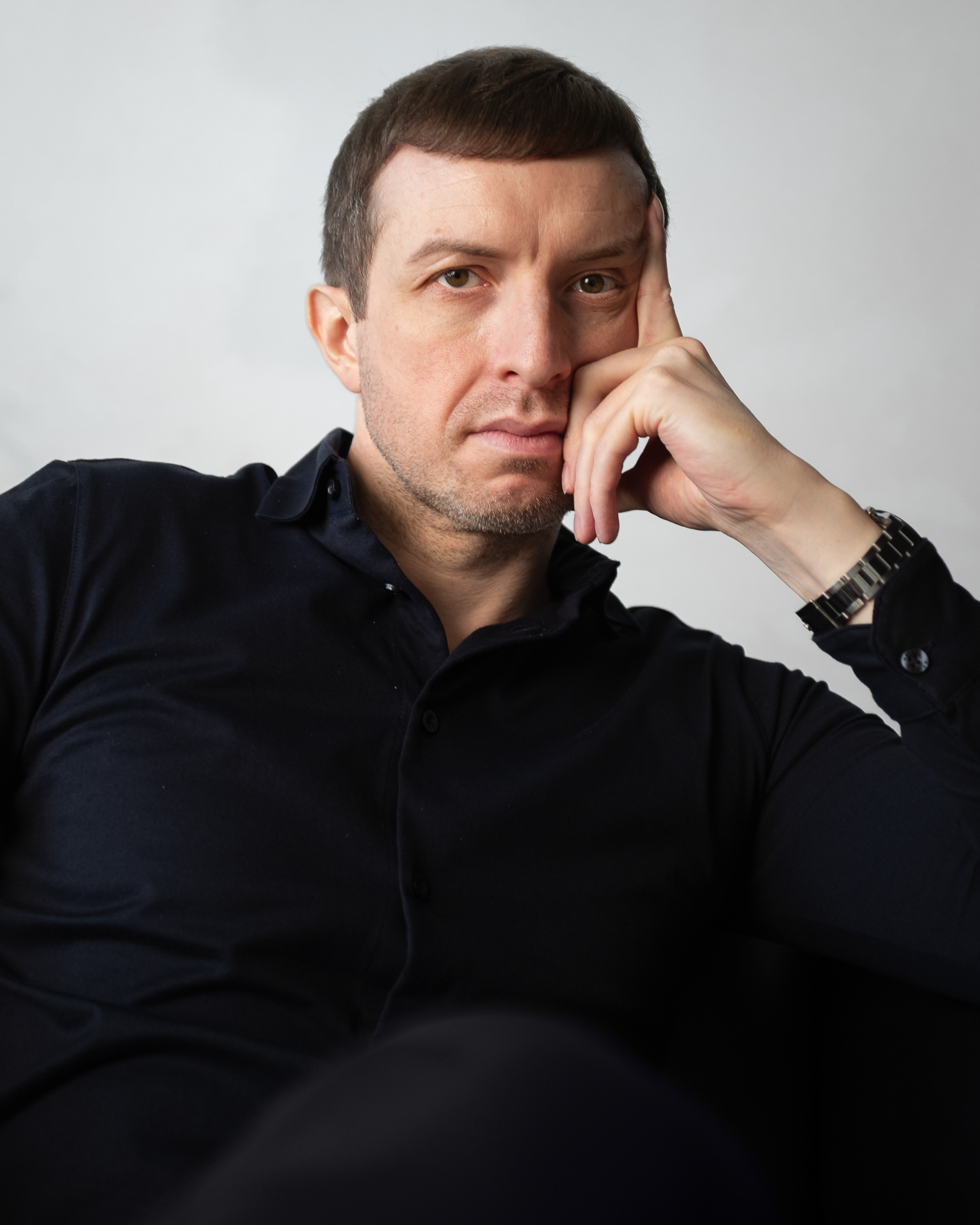 Michael Serwa performance coach wearing a black shirt and propping his head in his apartment in London