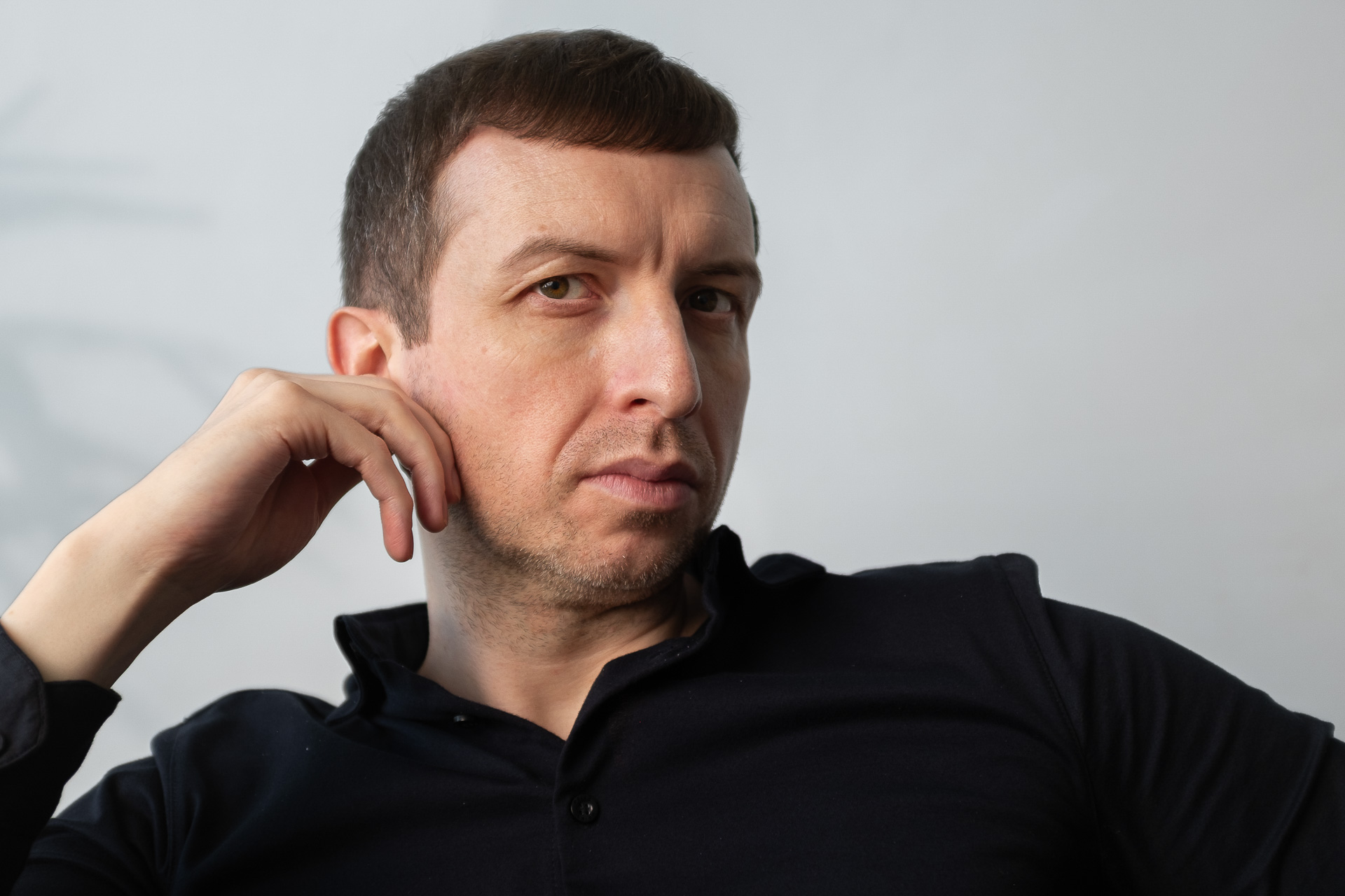 Michael Serwa performance coach touching his ear and wearing a black shirt in his apartment in London